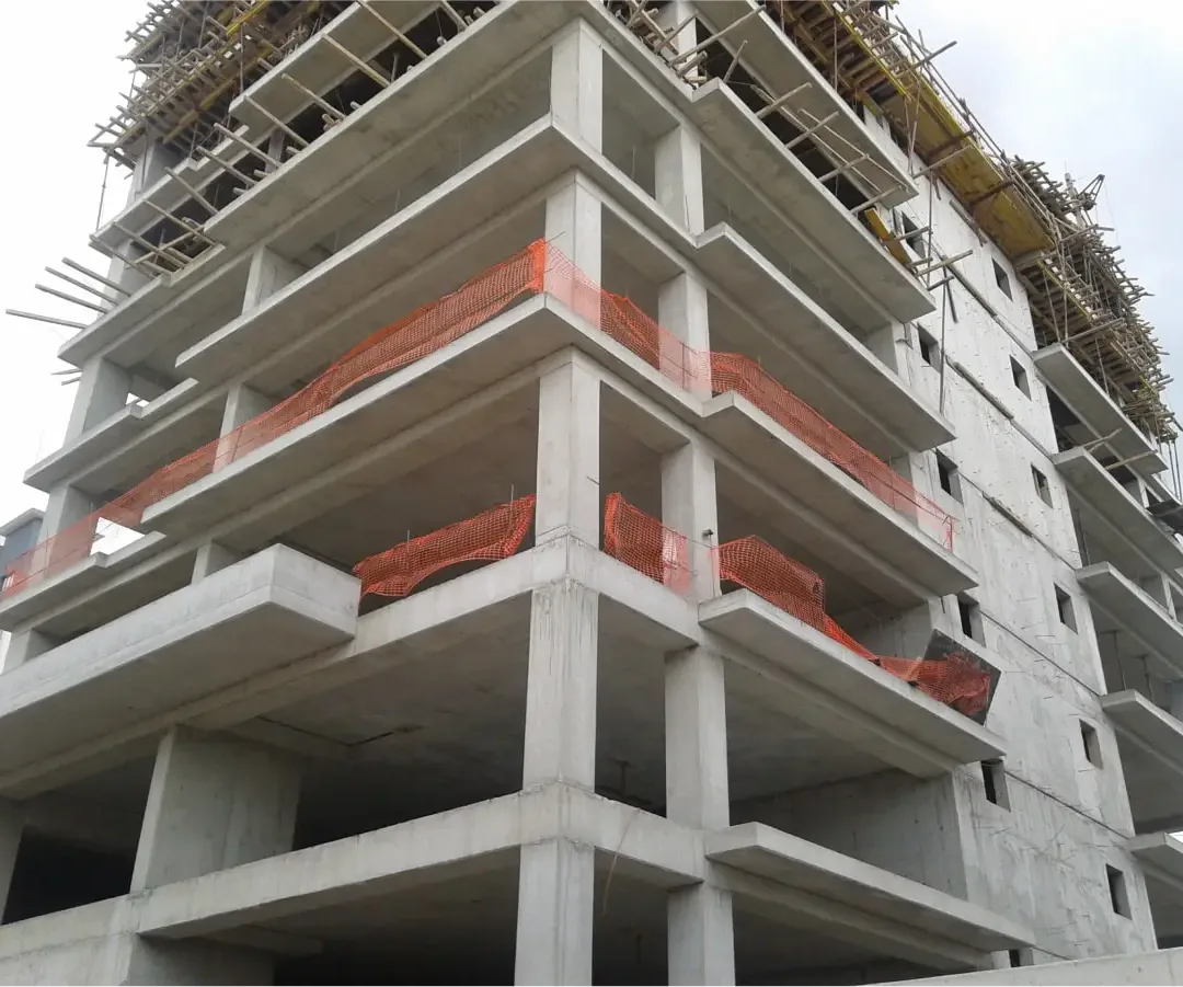 Photographie de chantier d'un bâtiment en béton armé en construction, avec filets de sécurité orange en rives de dalle